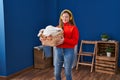 Young blonde woman listening to music holding basket with clothes at laundry room Royalty Free Stock Photo