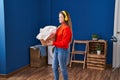 Young blonde woman listening to music holding basket with clothes at laundry room Royalty Free Stock Photo