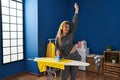 Young blonde woman listening to music ironing clothes at laundry room Royalty Free Stock Photo