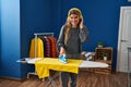 Young blonde woman listening to music ironing clothes at laundry room Royalty Free Stock Photo