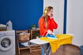 Young blonde woman listening to music ironing clothes at laundry room Royalty Free Stock Photo