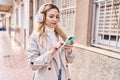 Young blonde woman listening to music with relaxed expression at street Royalty Free Stock Photo