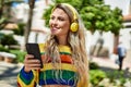 Young blonde woman listening to music from smartphone at the park Royalty Free Stock Photo