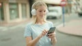 Young blonde woman listening to music standing at street Royalty Free Stock Photo