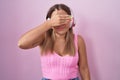 Young blonde woman listening to music using headphones covering eyes with hand, looking serious and sad Royalty Free Stock Photo