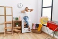 Young blonde woman listening to music waiting for washing machine at laundry room Royalty Free Stock Photo