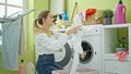 Young blonde woman listening to music washing clothes dancing at laundry room Royalty Free Stock Photo