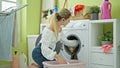 Young blonde woman listening to music washing clothes at laundry room Royalty Free Stock Photo