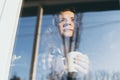 Young blonde woman looking out of the window with a concerned expression on her face Royalty Free Stock Photo