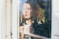 Young blonde woman looking out of the window with a concerned expression on her face Royalty Free Stock Photo