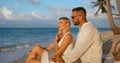 Young blonde woman and man in white shirt dating on evening beach, enjoying summer time Royalty Free Stock Photo