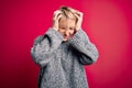 Young blonde woman with modern short hair wearing casual sweater over pink background suffering from headache desperate and Royalty Free Stock Photo