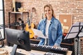 Young blonde woman musician playing piano keyboard at music studio Royalty Free Stock Photo