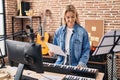 Young blonde woman musician playing piano keyboard at music studio Royalty Free Stock Photo