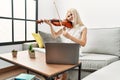 Young blonde woman musician smiling confident having online violin lesson at home