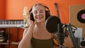 Young blonde woman musician smiling confident singing song at music studio