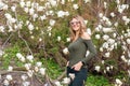 Young blonde woman near blossoming magnolia flowers tree in spring park on sunny day. Magnolia trees. Beautiful happy Royalty Free Stock Photo