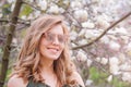 Young blonde woman near blossoming magnolia flowers tree in spring park on sunny day. Magnolia trees. Beautiful happy girl Royalty Free Stock Photo