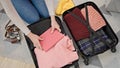 Young blonde woman packing clothes on suitcase for journey at home Royalty Free Stock Photo
