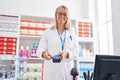 Young blonde woman pharmacist using credit card and dataphone at pharmacy Royalty Free Stock Photo