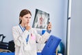 Young blonde woman physiotherapist looking xray thinking at rehab clinic