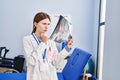 Young blonde woman physiotherapist looking xray thinking at rehab clinic