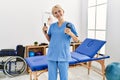 Young blonde woman physiotherapist smiling confident holding press hand tool at rehab clinic