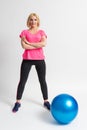 Woman in sportswear and sneakers goes in for sports with a fitness ball Royalty Free Stock Photo