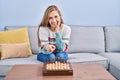 Young blonde woman playing chess sitting on the sofa smiling happy pointing with hand and finger Royalty Free Stock Photo