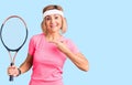 Young blonde woman playing tennis holding racket smiling happy pointing with hand and finger Royalty Free Stock Photo