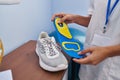 Young blonde woman podiatrist holding insole at clinic