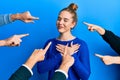 Young blonde woman with pointing fingers around her smiling with hands on chest, eyes closed with grateful gesture on face Royalty Free Stock Photo