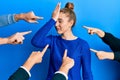 Young blonde woman with pointing fingers around her surprised with hand on head for mistake, remember error Royalty Free Stock Photo