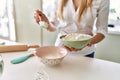 Young blonde woman pouring flour on bowl at kitchen Royalty Free Stock Photo