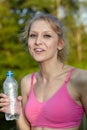 Young blonde woman runner holds blue bottle