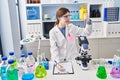 Young blonde woman scientist analysing test tube writing on clipboard at laboratory