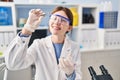 Young blonde woman scientist holding sample with tweezers at laboratory