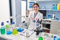 Young blonde woman scientist holding sample with tweezers at laboratory