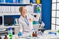 Young blonde woman scientist measuring liquid writing on document at laboratory Royalty Free Stock Photo