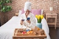 Young blonde woman shopping with smartphone and holding credit card having breakfast at bedroom Royalty Free Stock Photo