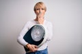 Young blonde woman with short hair holding scale for healthy weight and lifestyle cover mouth with hand shocked with shame for