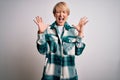 Young blonde woman with short hair wearing casual retro green shirt over  background celebrating mad and crazy for success Royalty Free Stock Photo