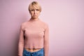 Young blonde woman with short hair wearing casual turtleneck sweater over pink background depressed and worry for distress, crying Royalty Free Stock Photo