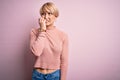 Young blonde woman with short hair wearing casual turtleneck sweater over pink background looking stressed and nervous with hands Royalty Free Stock Photo