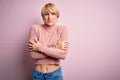 Young blonde woman with short hair wearing casual turtleneck sweater over pink background shaking and freezing for winter cold Royalty Free Stock Photo