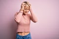 Young blonde woman with short hair wearing casual turtleneck sweater over pink background suffering from headache desperate and Royalty Free Stock Photo