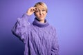 Young blonde woman with short hair wearing winter turtleneck sweater over purple background worried and stressed about a problem Royalty Free Stock Photo