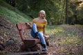 Young blonde woman sitting alone on a wooden bench in the forest Royalty Free Stock Photo