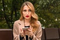 Young blonde woman is sitting on a Park bench and waiting for a phone call from her boyfriend Royalty Free Stock Photo