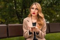 Young blonde woman is sitting on a Park bench and waiting for a phone call from her boyfriend Royalty Free Stock Photo